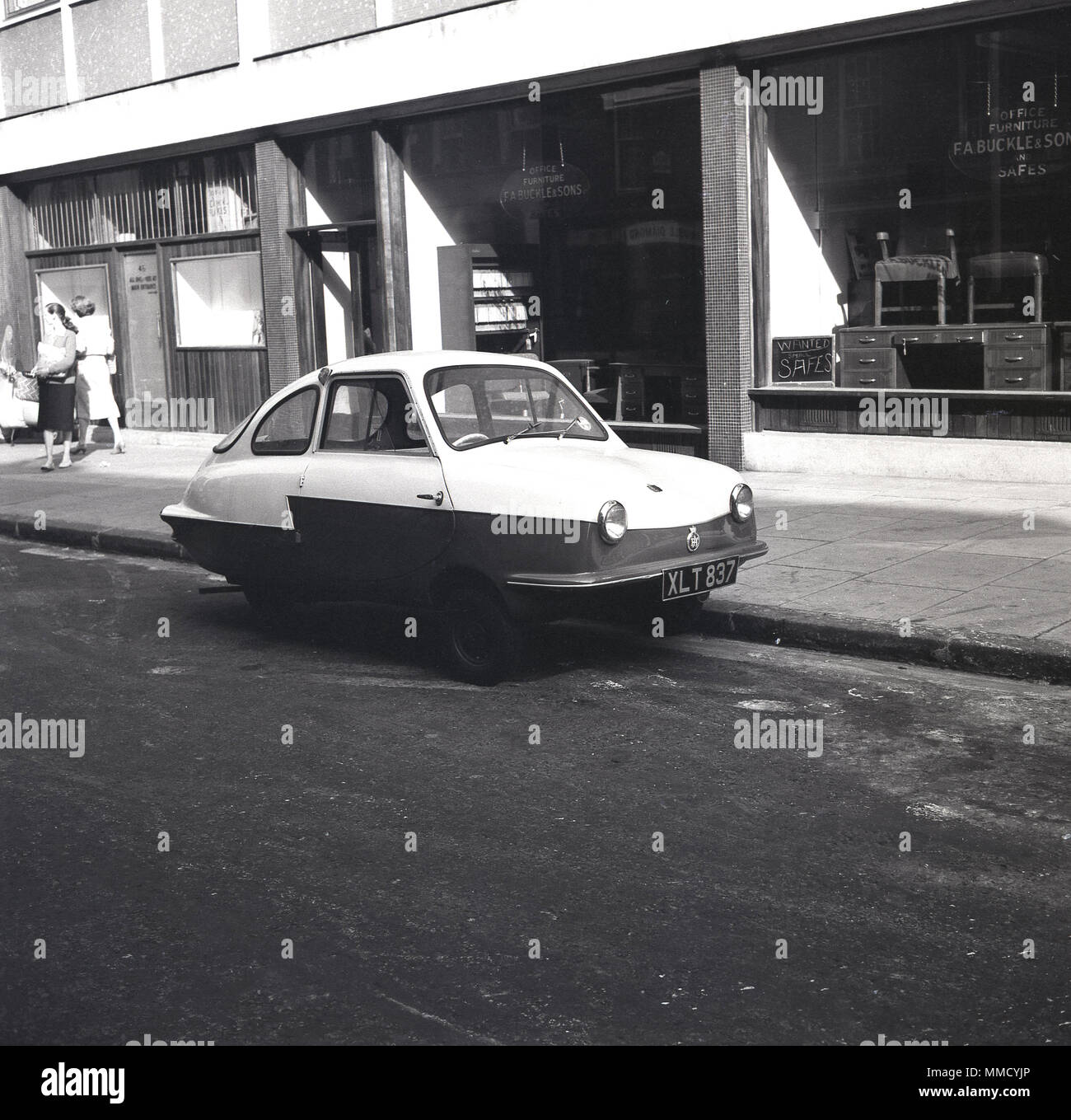 Années 1960, unusua à la petite voiture à trois roues' garé dans un quartier calme de la ville de Londres, en face de l'exposition de mobilier de bureau détaillant, F. UNE BOUCLE & Sons. Dans les années 50 et 60, trois-roues est devenue populaire, qu'ils pourraient l'être garé facilement et n'a pas besoin d'une licence séparée si vous possédiez un permis moto. Banque D'Images