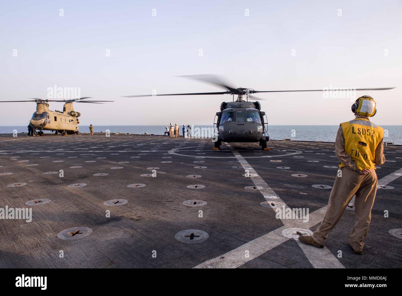 171002-N-OW019-397 U.S 5ÈME ZONE DES OPÉRATIONS DE LA FLOTTE (oct. 2, 2017) Marine Cpl. Ryan Carr, originaire de Oceanside, California, affectés à la lutte contre le service cargo à bord du navire de débarquement quai amphibie USS Pearl Harbor (LSD 52), observe les opérations de vol avec un UH-60 et un CH-47D Chinook de l'armée, tous deux assignés à la Compagnie Bravo, 2e Bataillon, 149e bataillon de l'aviation d'appui général (GSAB). Pearl Harbor est une partie de l'Amérique du groupe amphibie (ARG) et, avec l'entrepris 15e Marine Expeditionary Unit (MEU), est déployé à l'appui d'opérations de sécurité maritime et sécurité théâtre g Banque D'Images