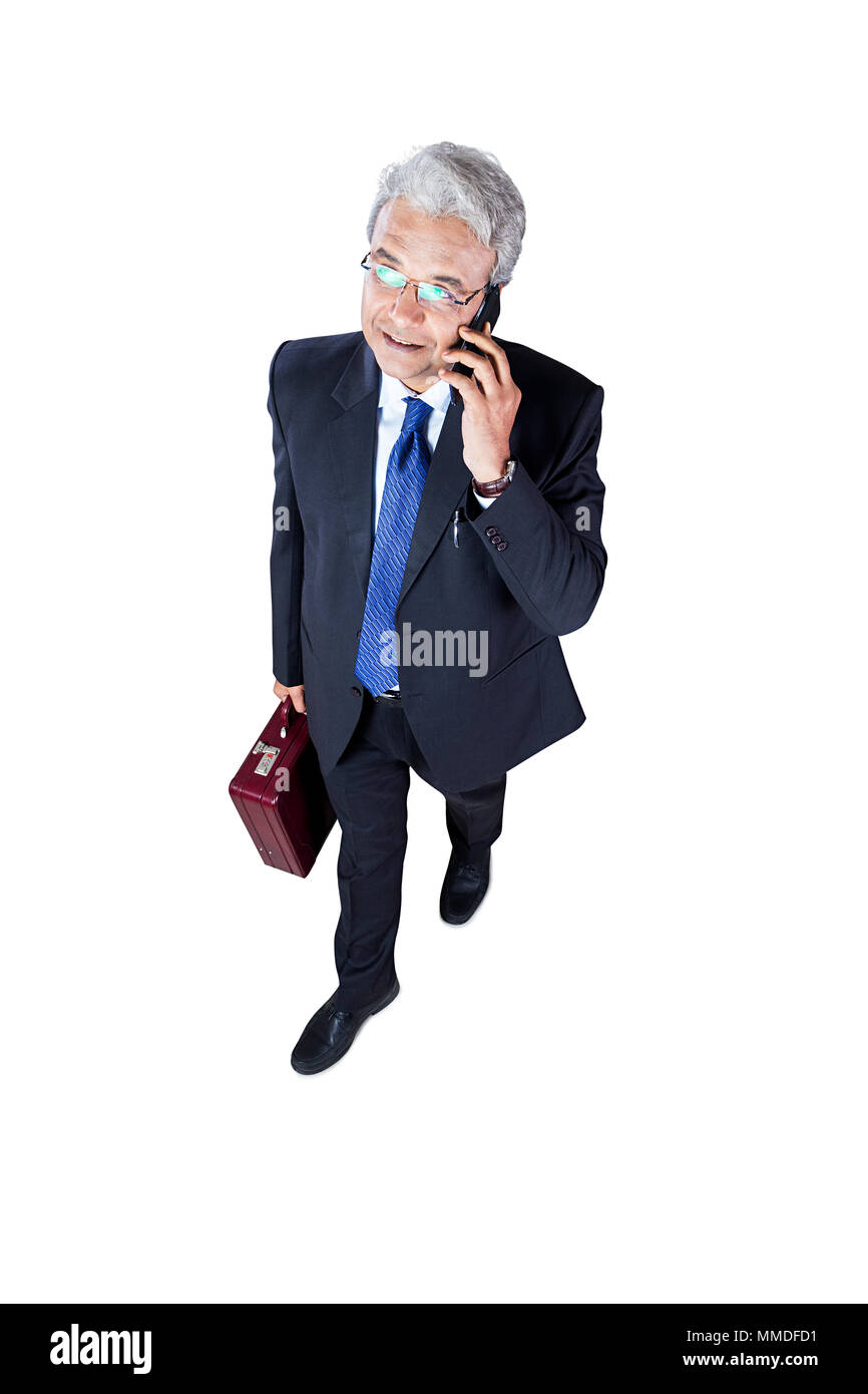 Un Senior Businessman Walking and Talking On Mobile-Phone Fond blanc Banque D'Images