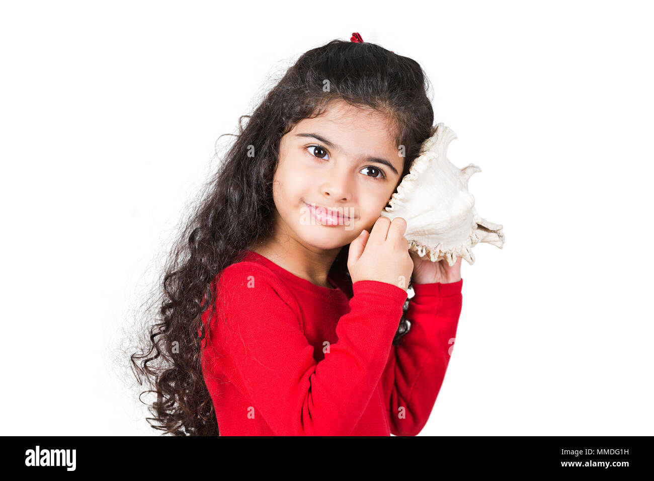 Une petite fille à l'écoute de sons de la mer dans le Seashell Banque D'Images