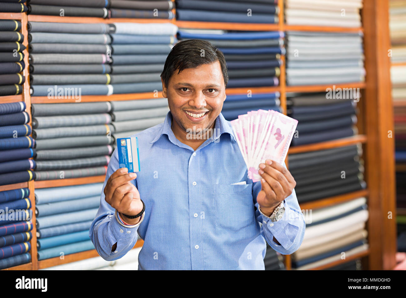 Un commerçant de vêtements montrant roupies avec Debit-Card In clothes store Banque D'Images
