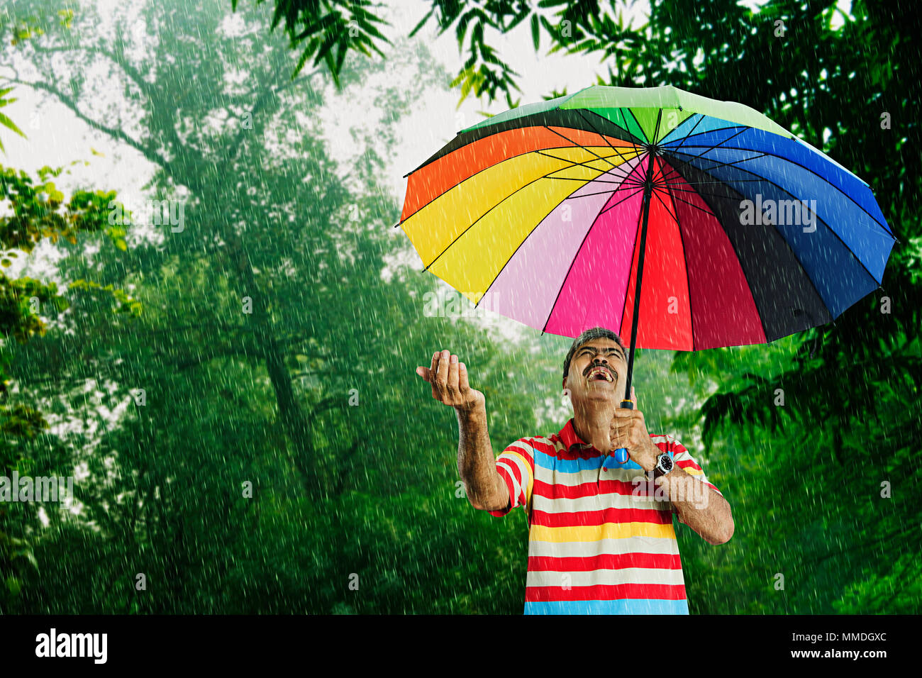 Un vieil homme gai parapluie sous la pluie qui Having-Fun Park Banque D'Images
