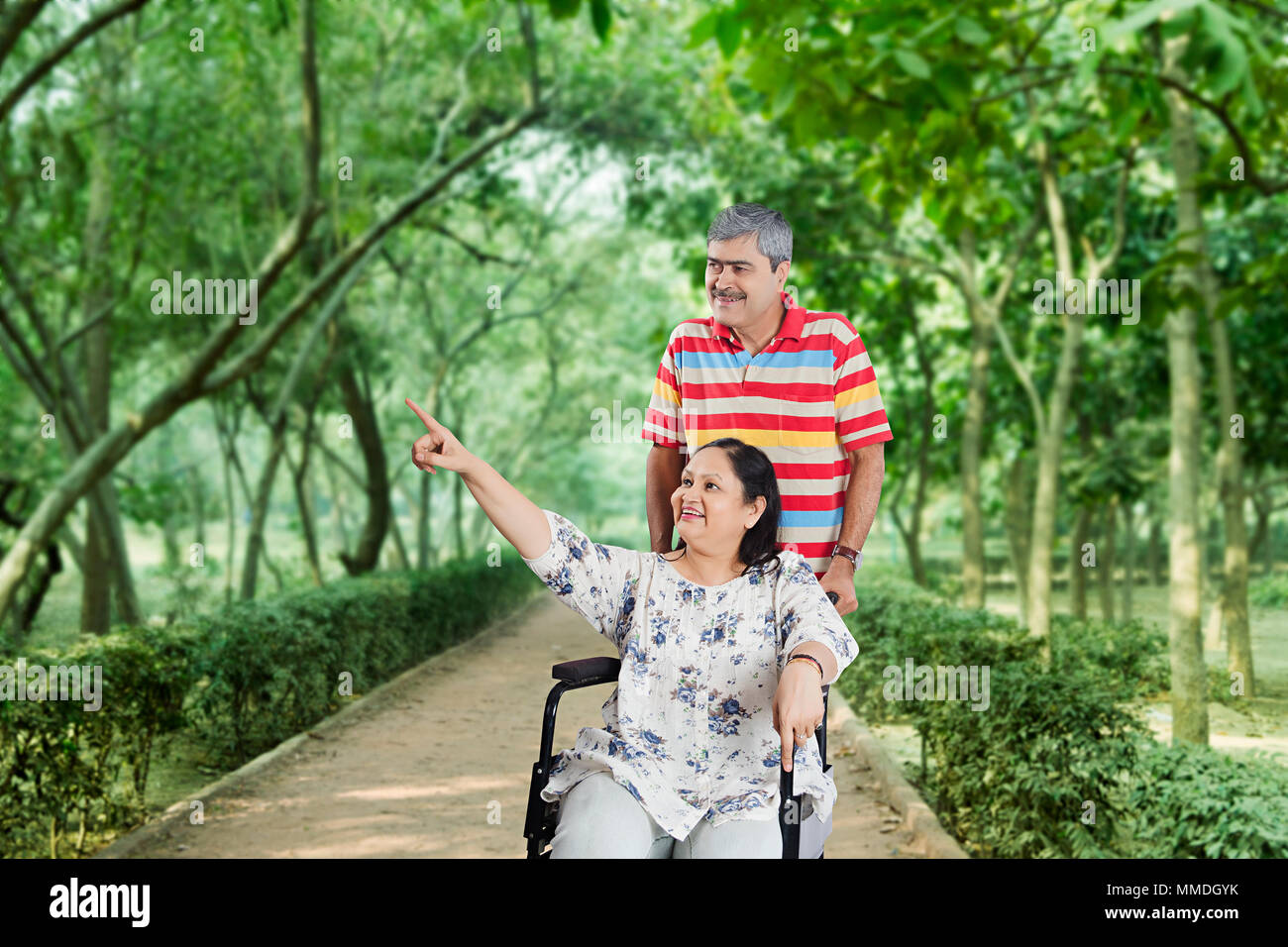 Couple de personnes âgées jouissant de sa marche, In-Park femme étant en fauteuil roulant Banque D'Images