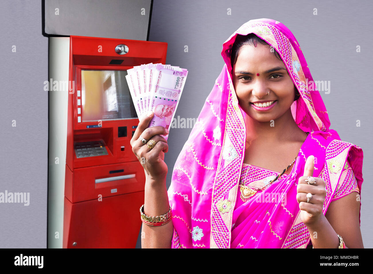 Une femme rurale Showing Thumbs-up avec Roupies indiennes se retirer en espèces DISTRIBUTEUR AUTOMATIQUE Banque D'Images