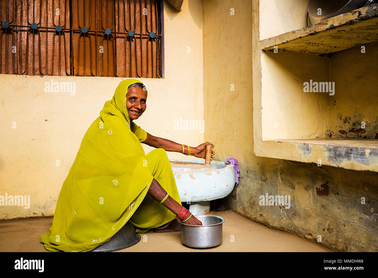 Une femme rurale moulant le blé avec moulin manuel d'assistance à domicile Village Banque D'Images