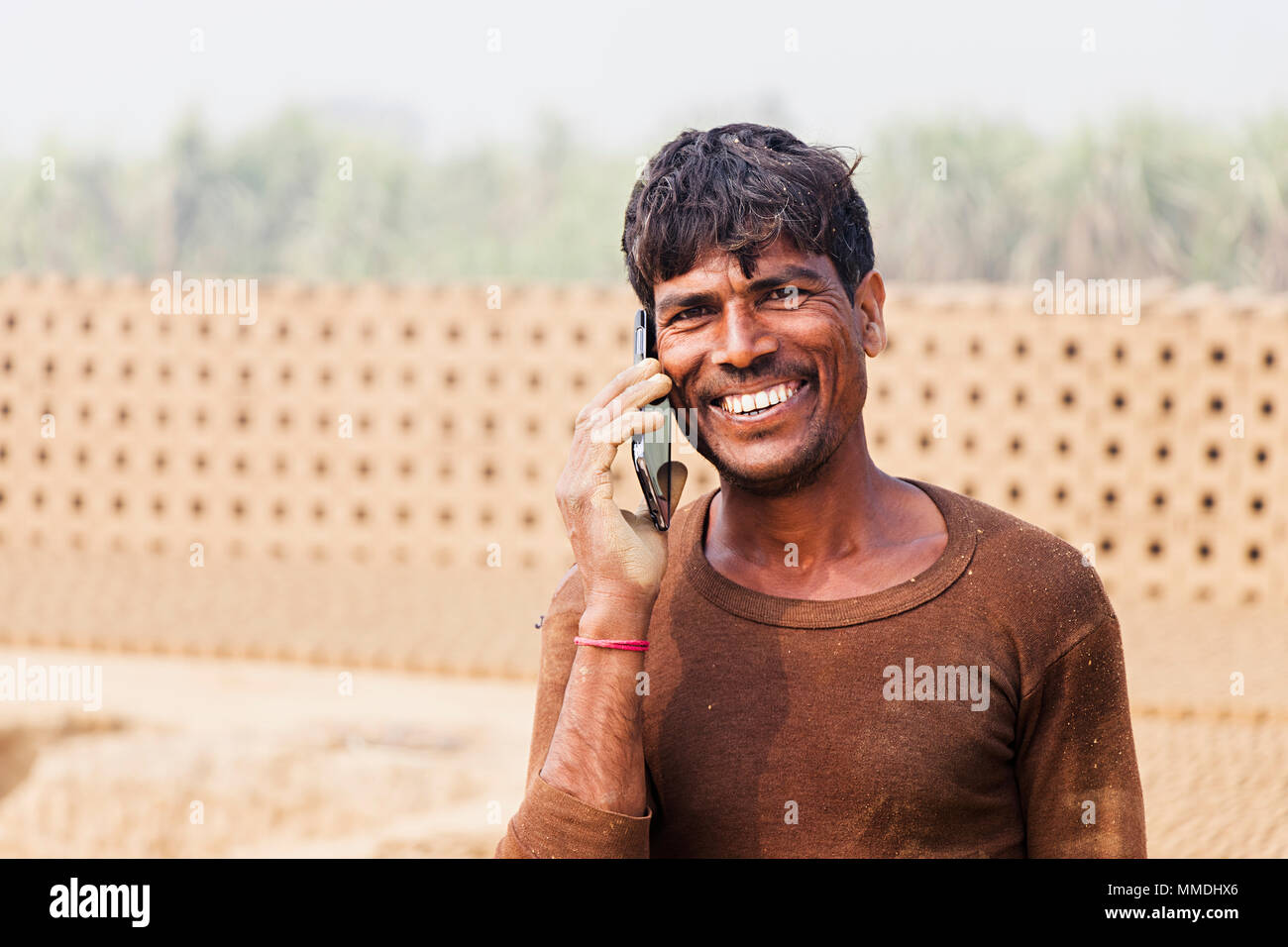 Un homme de main-d'Talking On Cellphone village rural d'usine en brique Banque D'Images