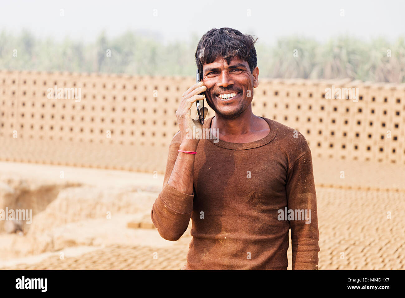 Un homme de main-d'Talking On Cellphone Smiling In-Village brick factory Banque D'Images