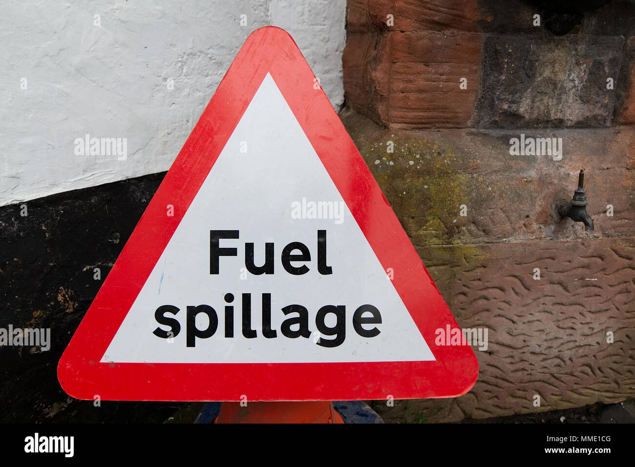 Triangulaire rouge et la sécurité routière les déversements de carburant avertissement signe un texte noir sur fond blanc contre wall with copy space Banque D'Images