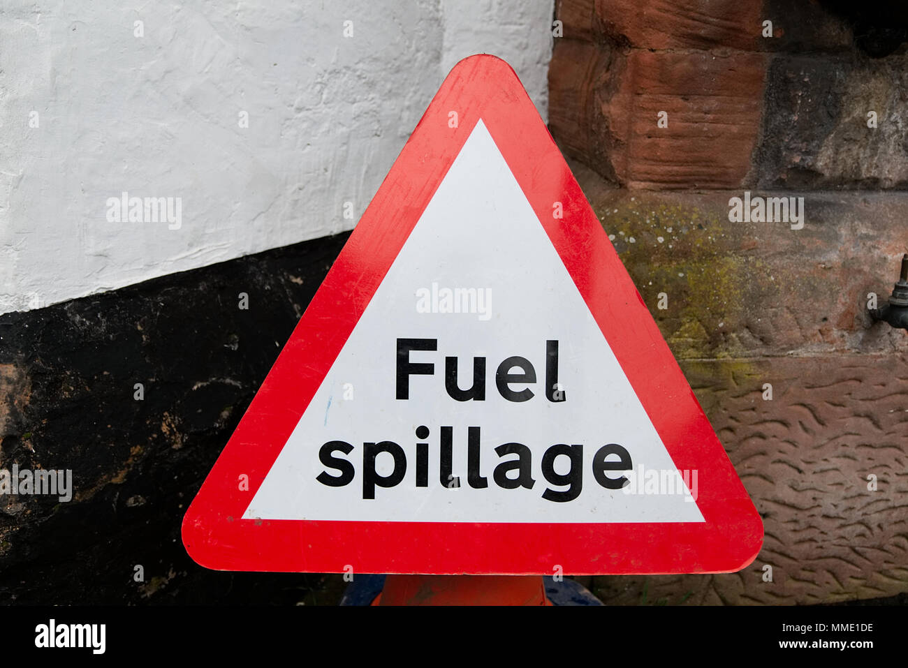 Triangulaire rouge et la sécurité routière les déversements de carburant avertissement signe un texte noir sur fond blanc contre wall with copy space Banque D'Images