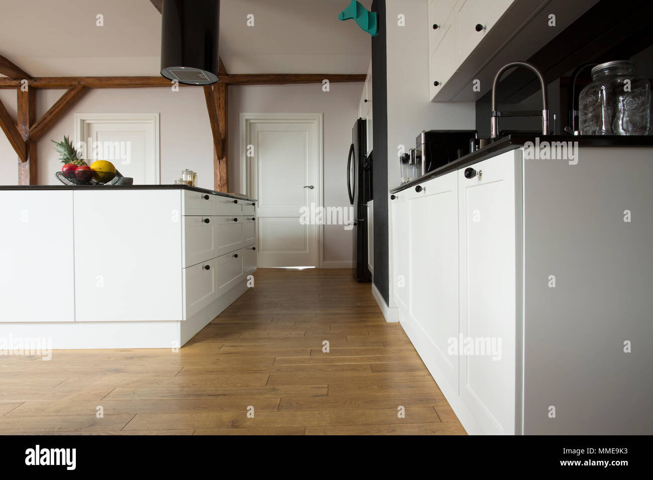 Low angle view of a modern cuisine intérieur avec plancher en bois, armoires et comptoir noir blanc Banque D'Images
