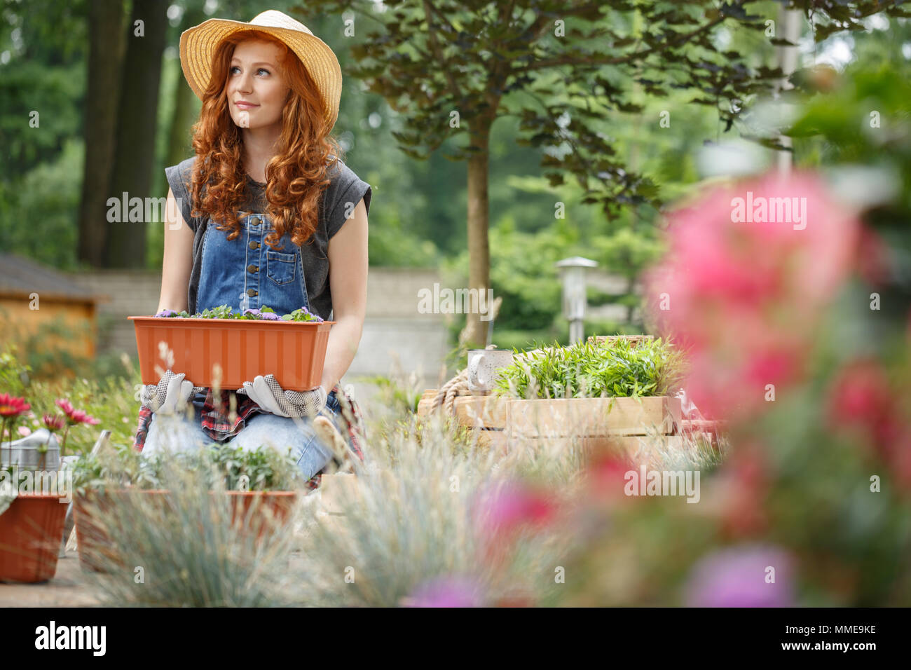 Jardinier souriant femme avec un chapeau de paille et fort avec des plantes  pendant le travail dans le jardin Photo Stock - Alamy