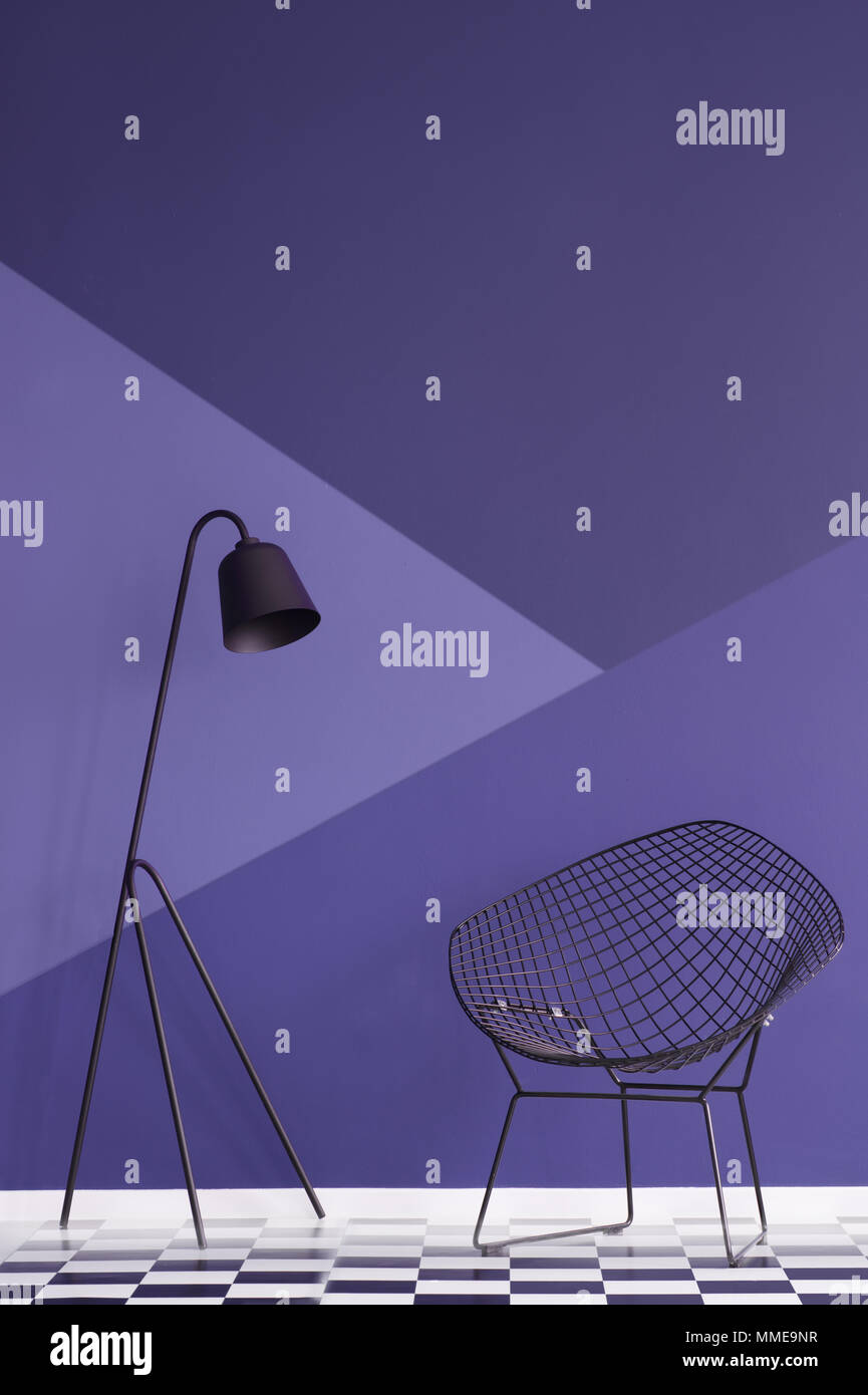 Violet asymétrique wall in modern living room intérieur avec lampe métallique et noir fauteuil sur plancher à carreaux. Photo réelle Banque D'Images