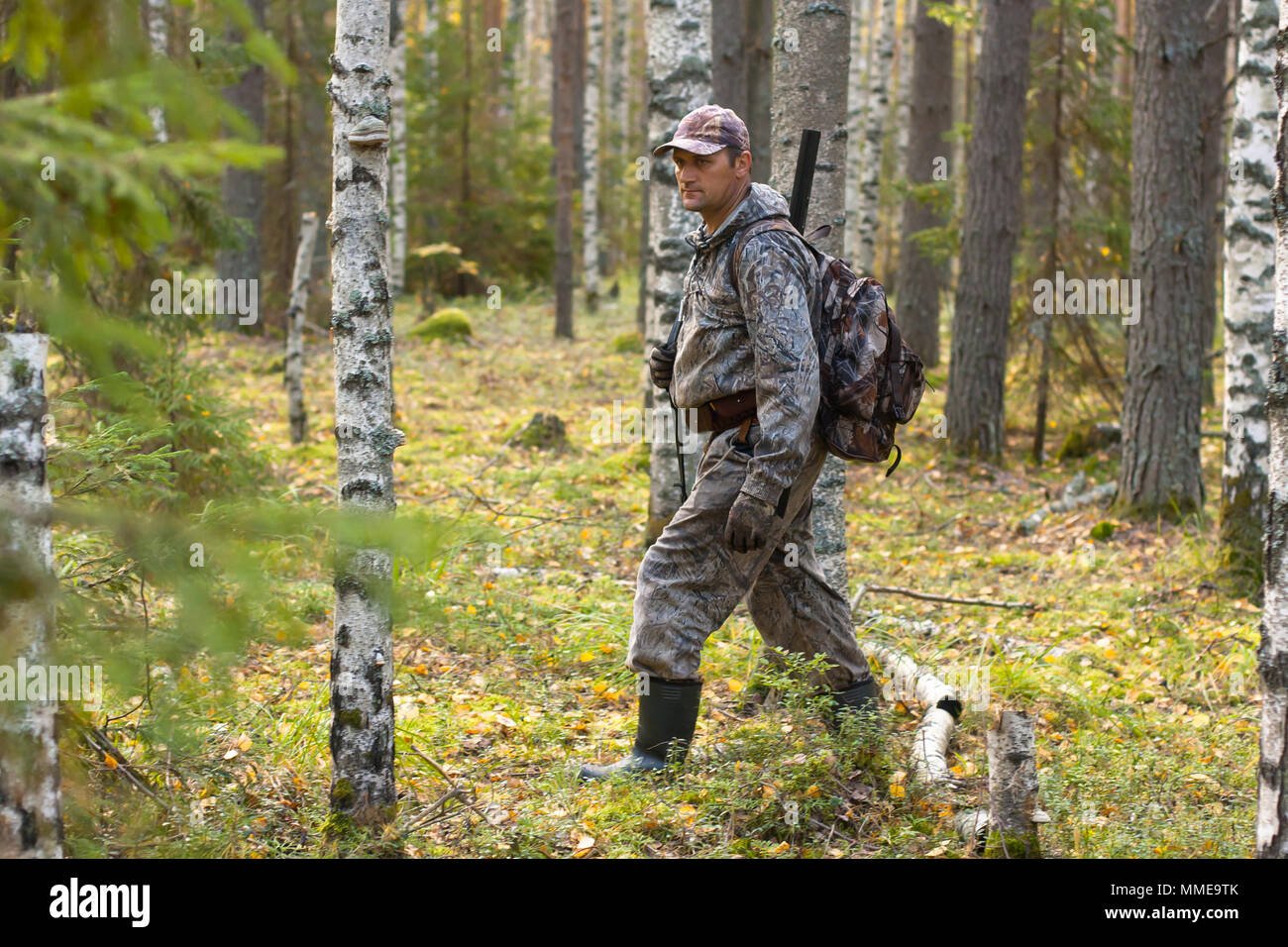 Hunter in camouflage marche à travers la forêt Banque D'Images