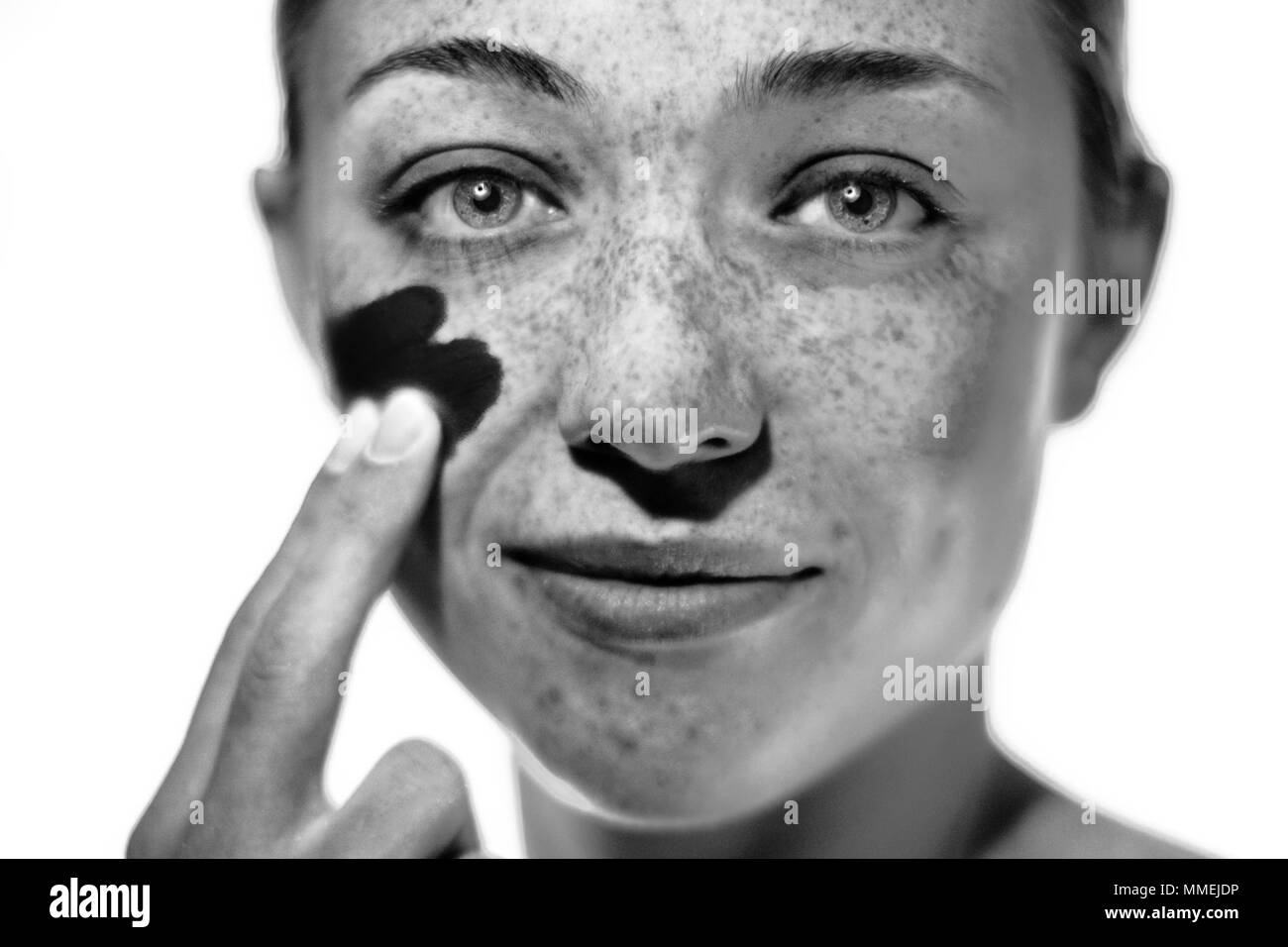 Parution du modèle. Appliquez un écran solaire femme sur sa joue. Banque D'Images