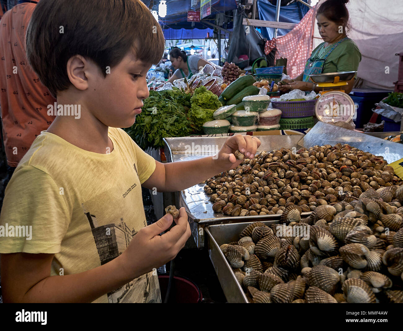 La curiosité. Jeune garçon curieusement l'étude des escargots dans un marché de rue en Thaïlande, wc séparés. Banque D'Images