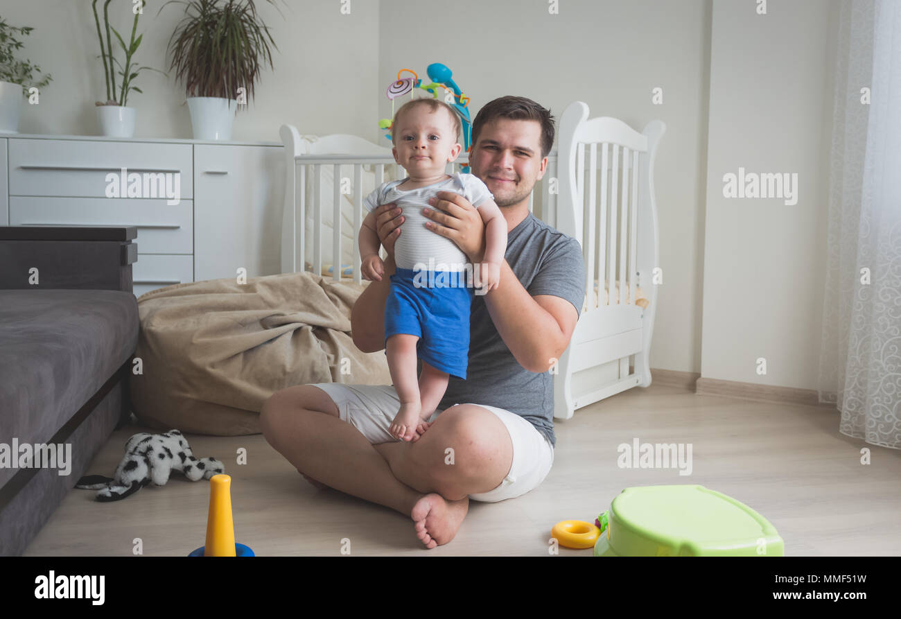 Photo de ton sourire heureux père tenant son bébé âgé de 10 mois fils Banque D'Images