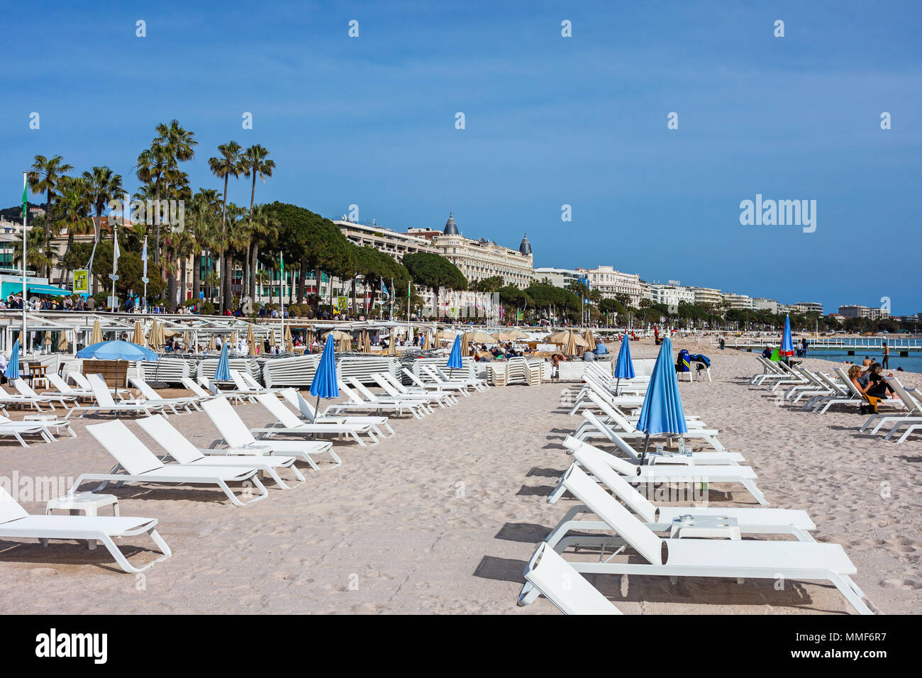 France, Cannes, plage avec transats sur azur à la mer Méditerranée, les bâtiments le long du boulevard de la Croisette Banque D'Images