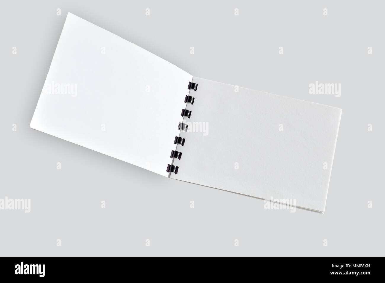 Ordinateur portable ouvert vierge ou une brochure avec spirale en plastique noir close up, isolé sur gris clair. Le bloc-notes, papier journal organisateur page ou album - maquette Banque D'Images