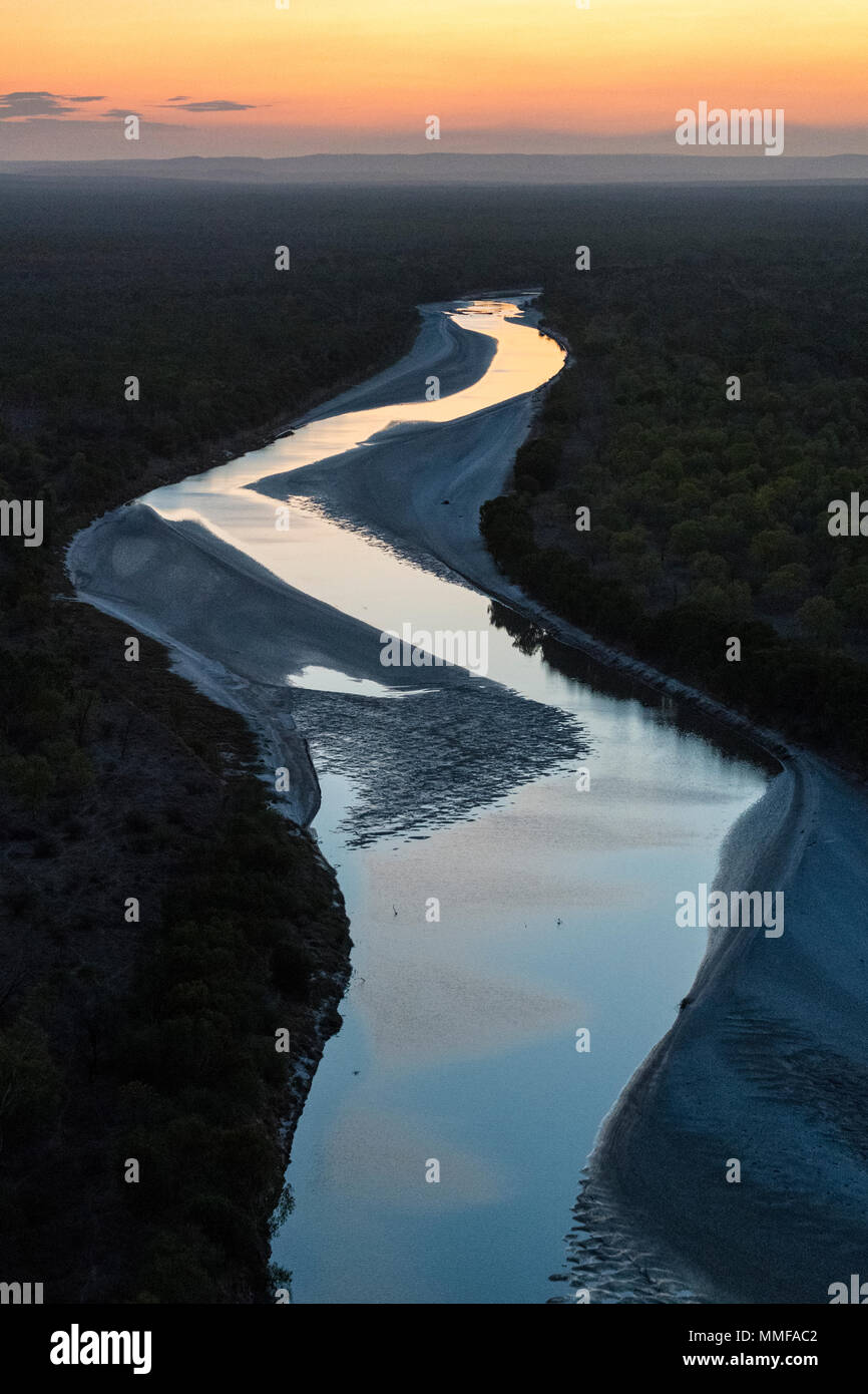 Le coucher du soleil d'incandescence la réflexion sur une grande marée en rivière qui coule à travers un outback cattle station à distance. Banque D'Images