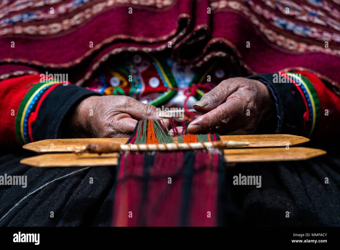 Les mains trempées et surmonté d'une vieille femme Quechua le tissage de laine de lama. Banque D'Images