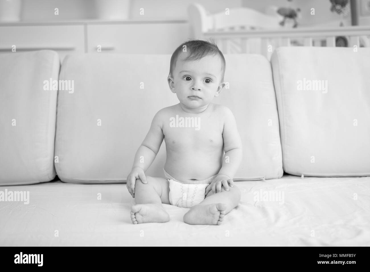 Photo en noir et blanc d'indiapers triste baby boy sitting on sofa Banque D'Images