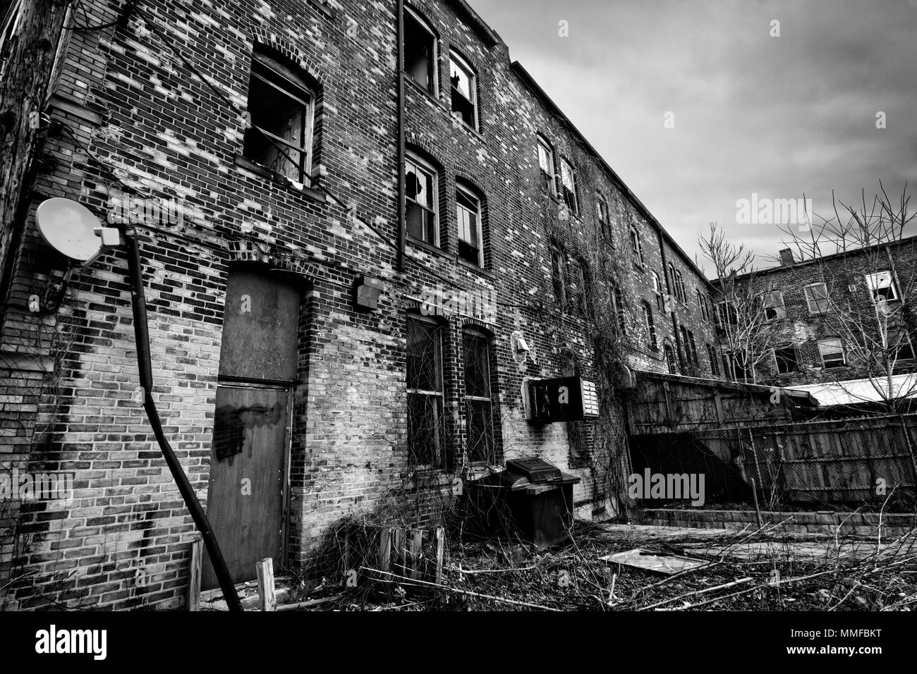 Photo en noir et blanc d'un vieux bâtiment en brique délabré en milieu urbain. Ce sont malheureusement souvent vu dans American la cites. Banque D'Images