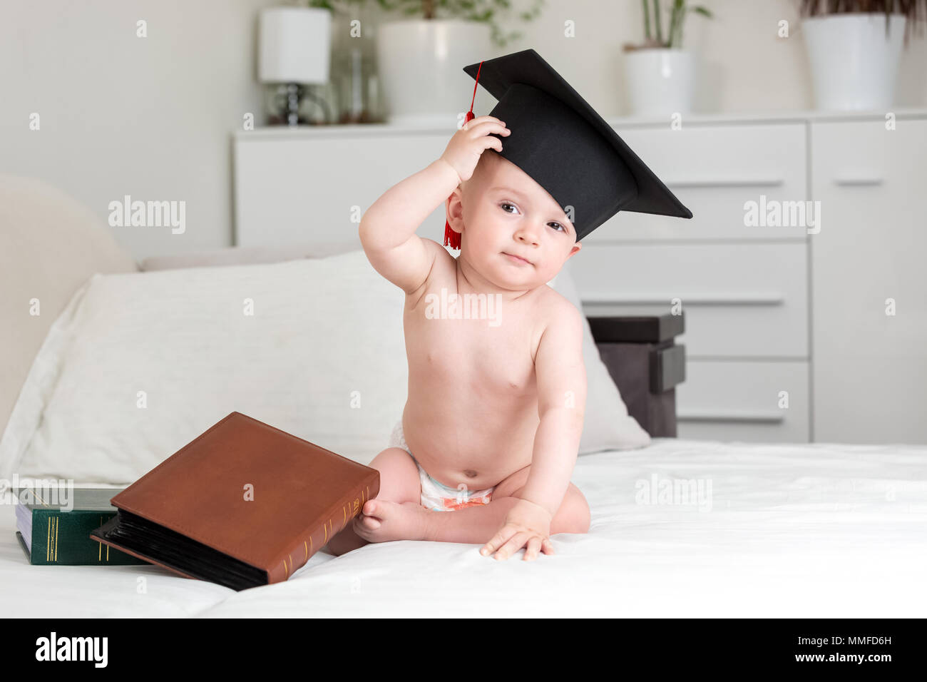 Mignon bébé baby genius dans university graduation cap frottant le front et  à huis clos. Concept de l'éducation des jeunes enfants Photo Stock - Alamy