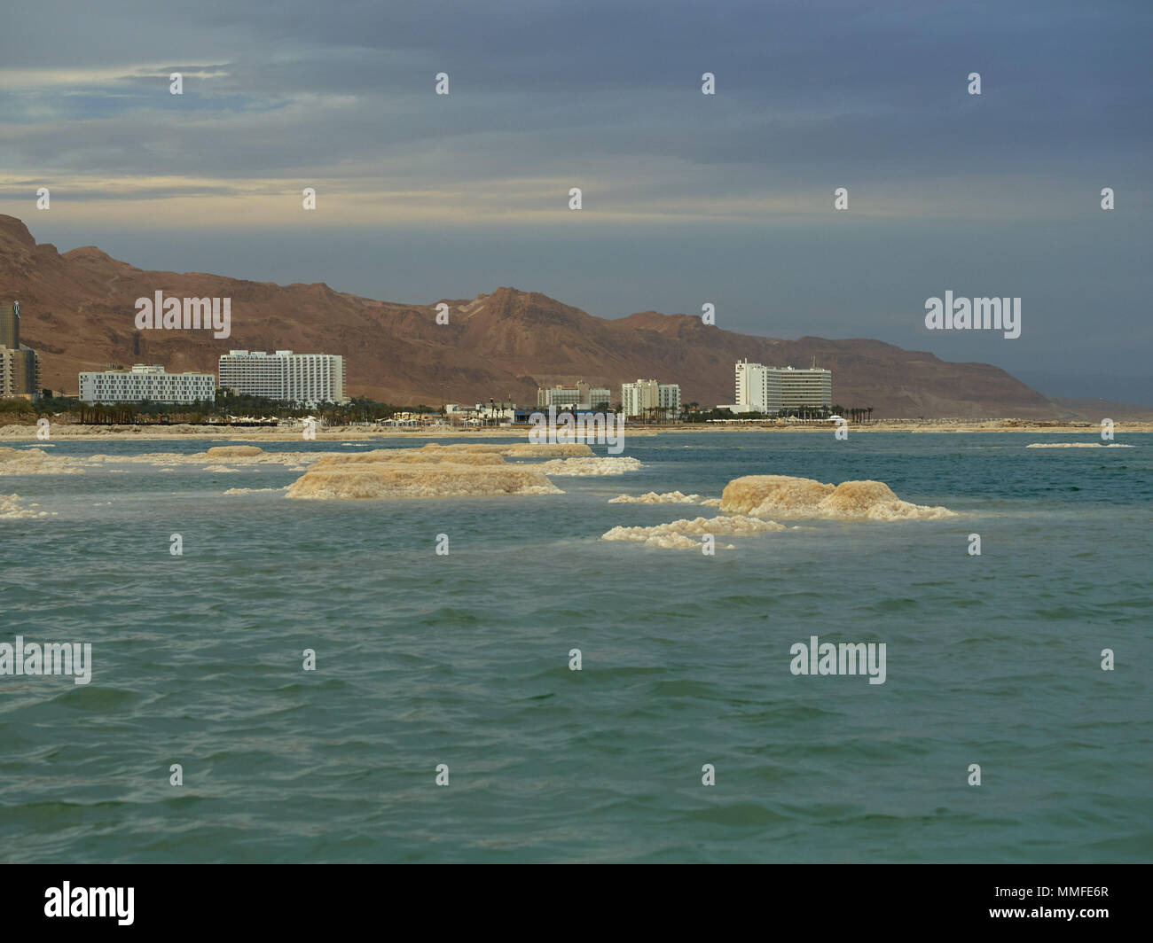 Rivage de la Mer Morte avec les bâtiments de l'ancien sanatorium, au premier plan l'eau bleue, Israël. Banque D'Images
