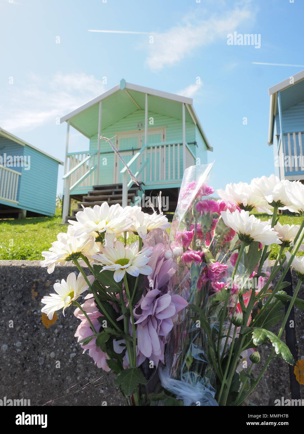 Minster sur mer, Kent, UK. Le 11 mai, 2018. Météo France : une chaude journée ensoleillée à Minster sur mer, Kent. Des fleurs à un être cher sur un mémorial banc en face de la plage des huttes. Credit : James Bell/Alamy Live News Banque D'Images