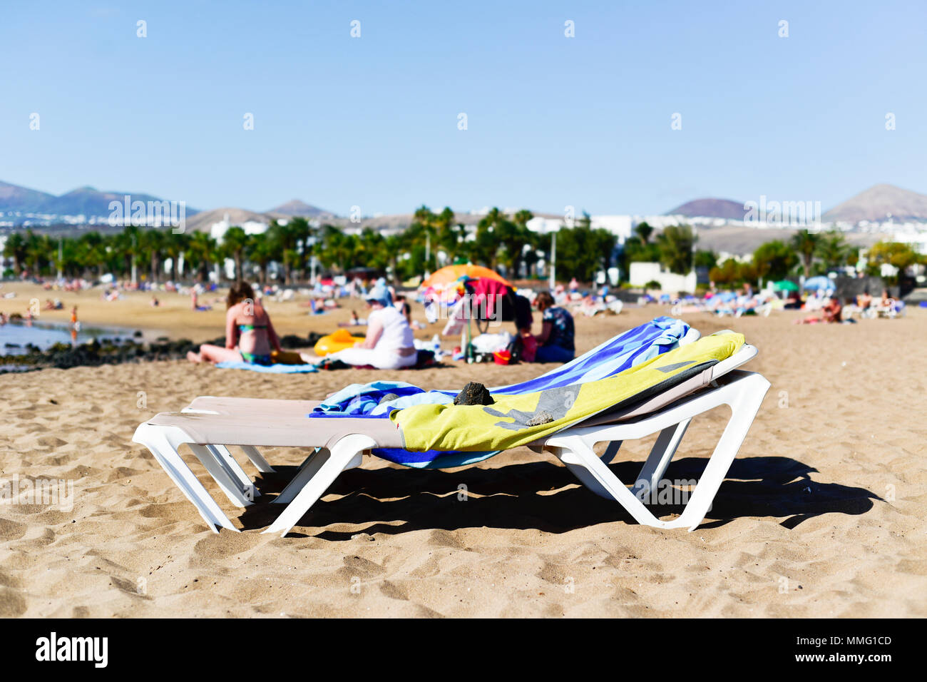 Chaises longues et méconnaissable les gens se détendre à la plage de la plage de Matagorda à Puerto del Carmen, Lanzarote, dans les îles Canaries, Espagne Banque D'Images