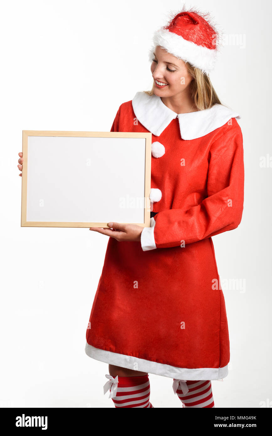 Beautiful happy blonde woman in Santa Claus clothes smiling avec tableau blanc dans ses mains. Jeune femme aux yeux bleus, isolated on white Banque D'Images