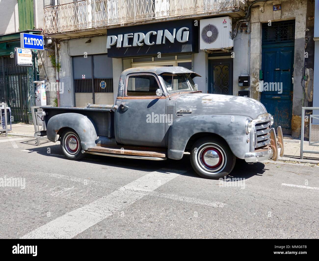 Vieux, gris, érodés, classic 1953 GMC 100 camionnette avec garniture en bois, vu dans la rue en face de tatouage, perçage, Avignon, France Banque D'Images