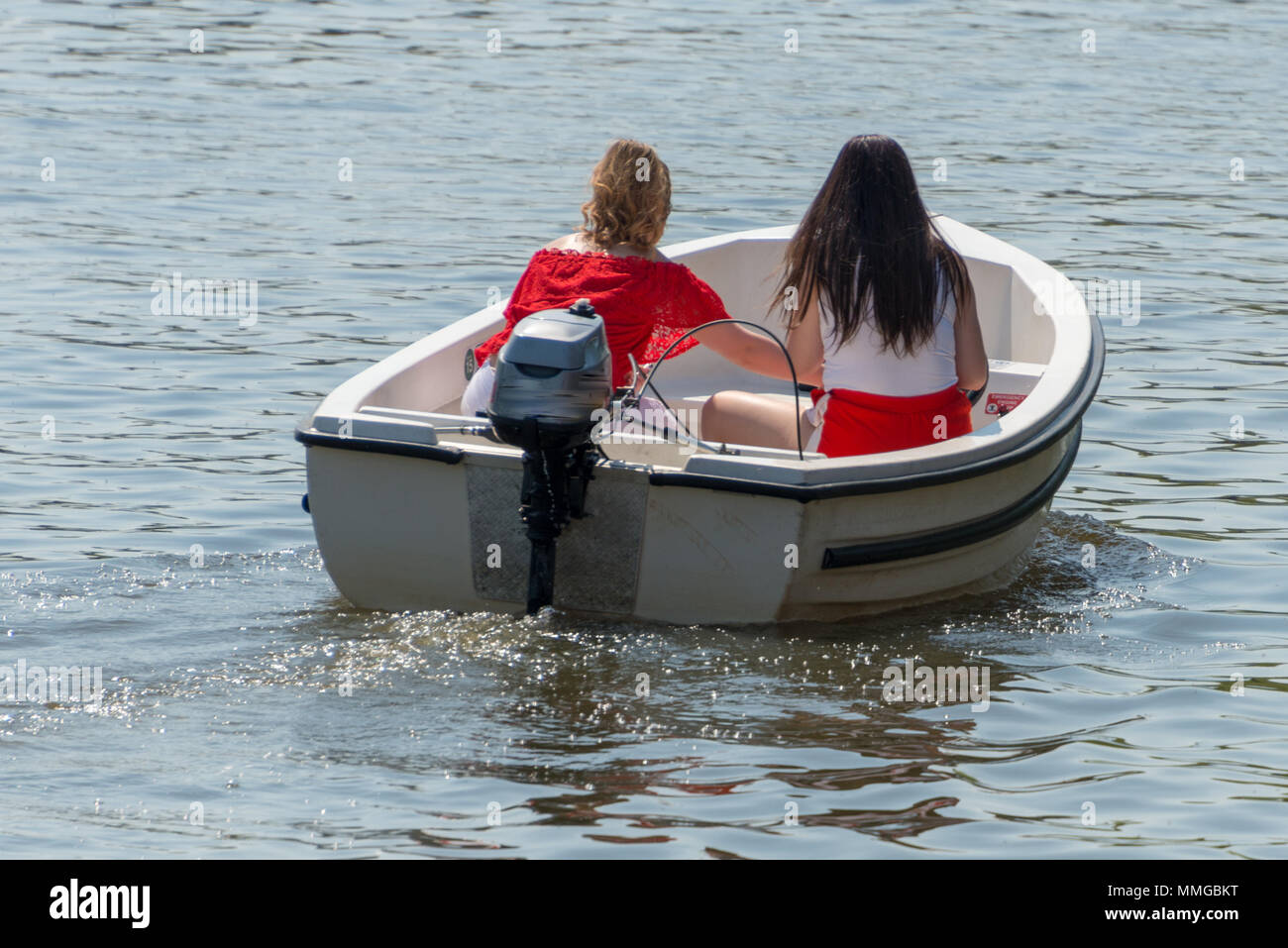 Deux filles en tenues rouges et blanches de la conduite de bateau sur rivière dans au milieu de l'été en tenant vos autoportraits et avoir conversation Banque D'Images