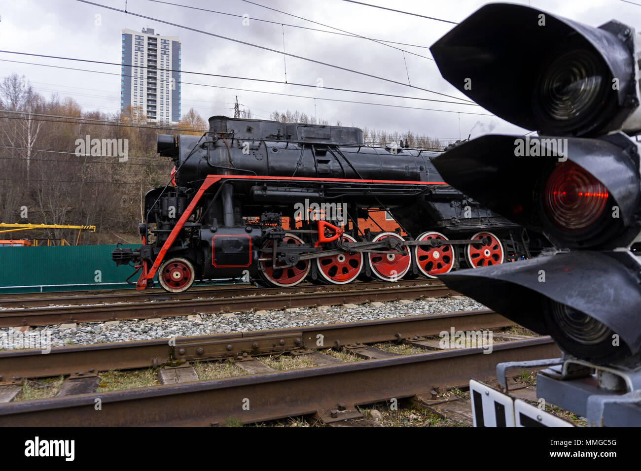 Locomotive vintage en raison de feuilles d'un feu de circulation à l'avant-plan sur la modernisation de la gare ferroviaire Banque D'Images