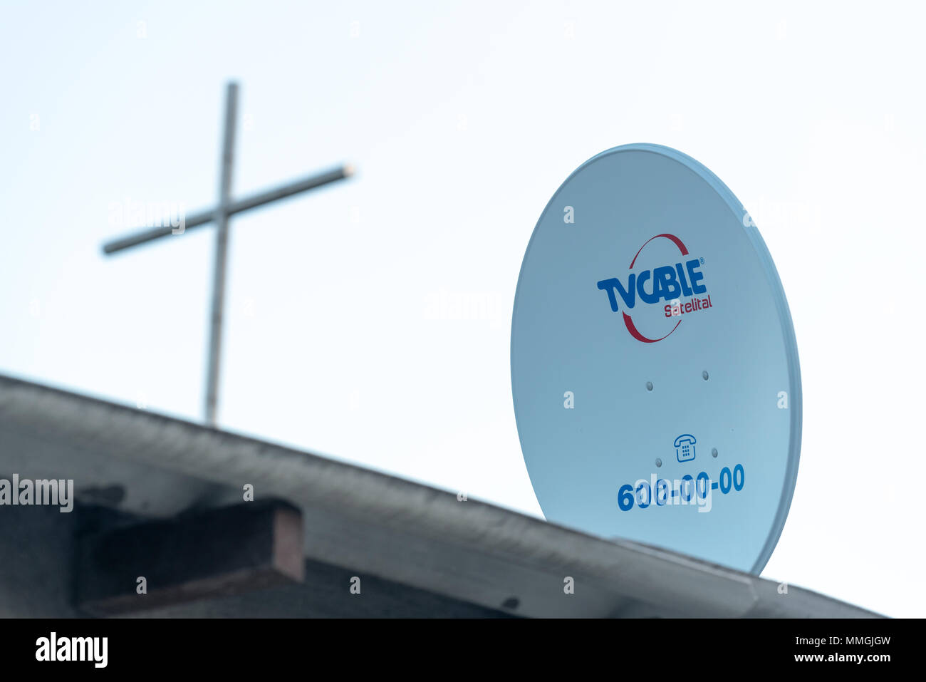 Antenne satellite sur le toit d'une maison et d'une croix au sommet d'une église voisine, Puerto Villamil, îles Galapagos, en Équateur. Banque D'Images