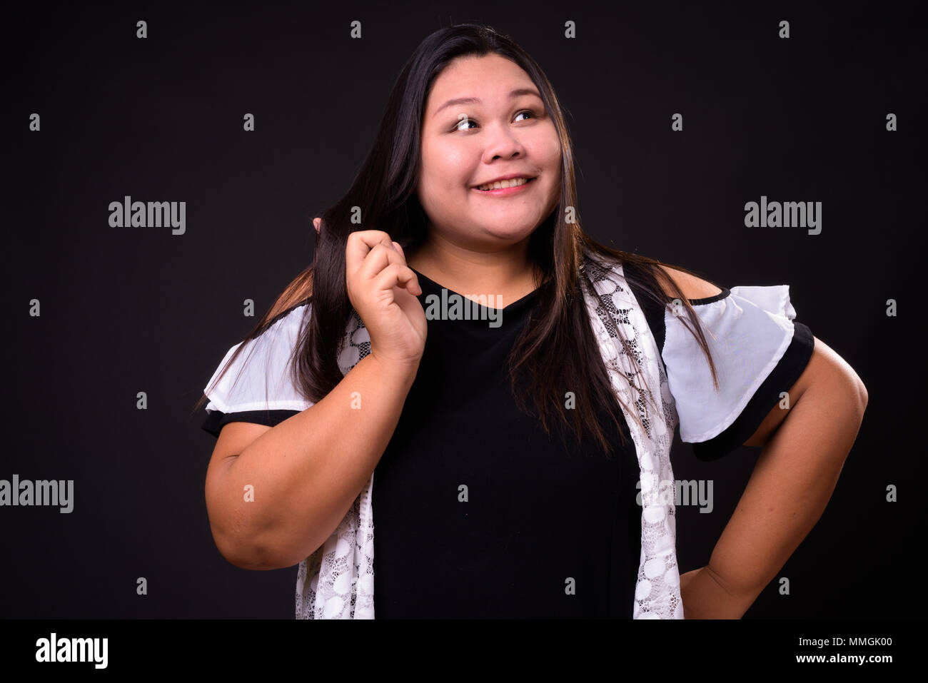 Belle femme asiatique en surpoids sur fond noir Banque D'Images