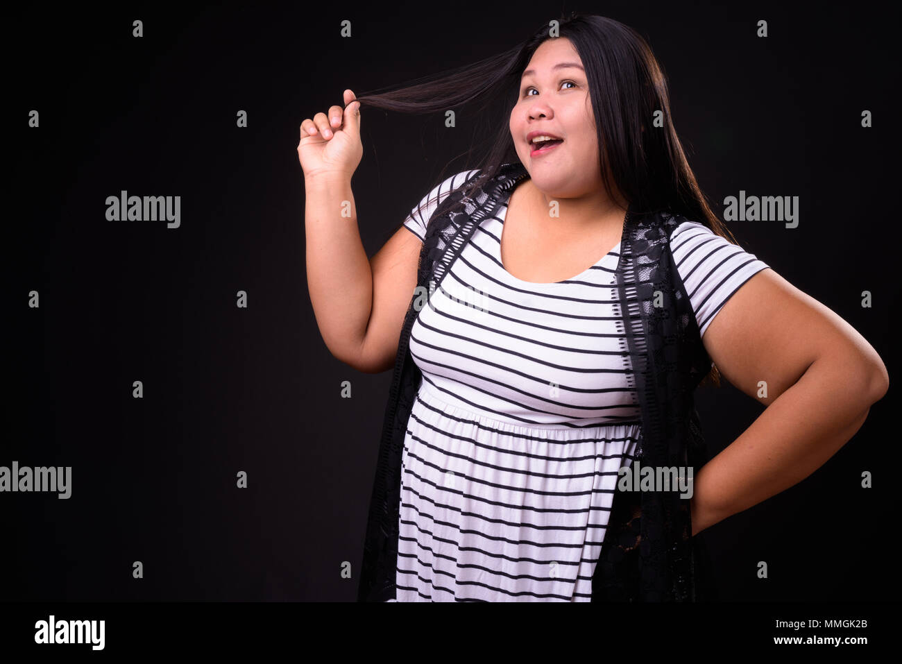 Belle femme asiatique en surpoids sur fond noir Banque D'Images