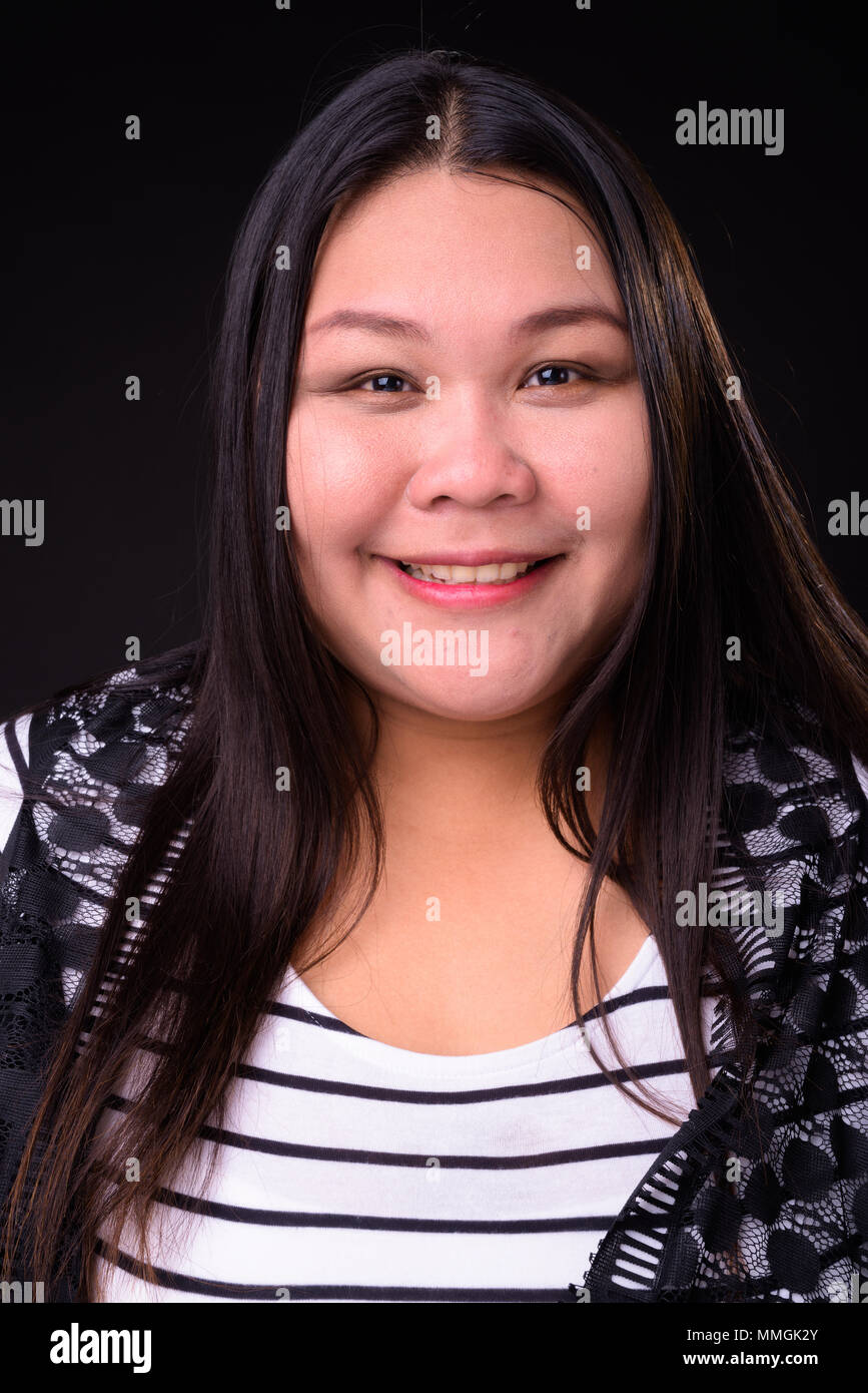 Belle femme asiatique en surpoids sur fond noir Banque D'Images