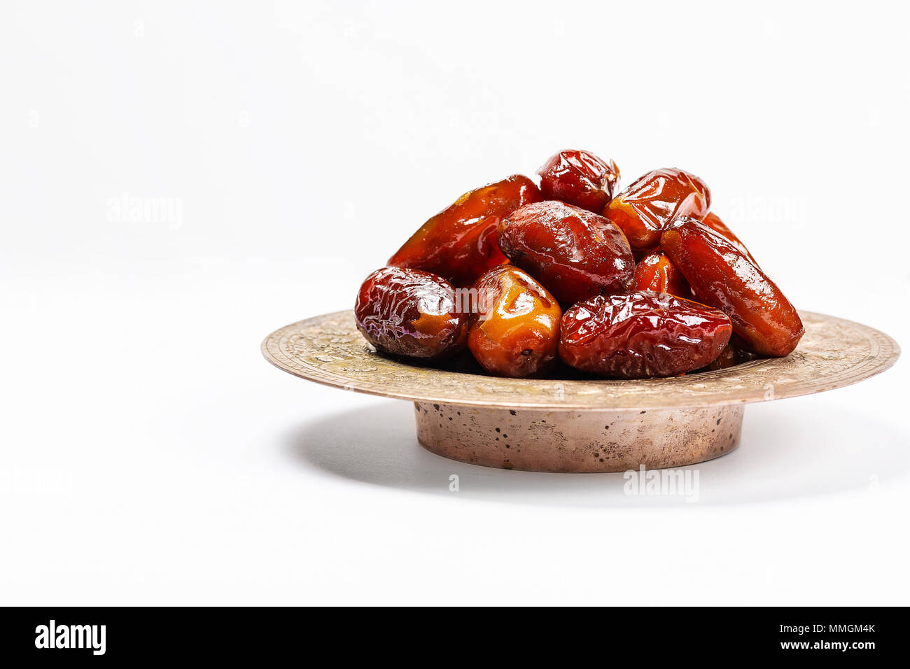 Dattes séchées sur un plateau traditionnel sur un fond blanc. Ramadan Kareem Banque D'Images