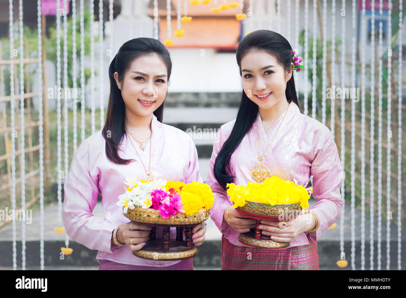 Portrait de belles femmes thaïlandaises sont en costume national thaïlandais sur l'échelle de naga permanent devant le temple et tenir fleurs jaunes. Banque D'Images