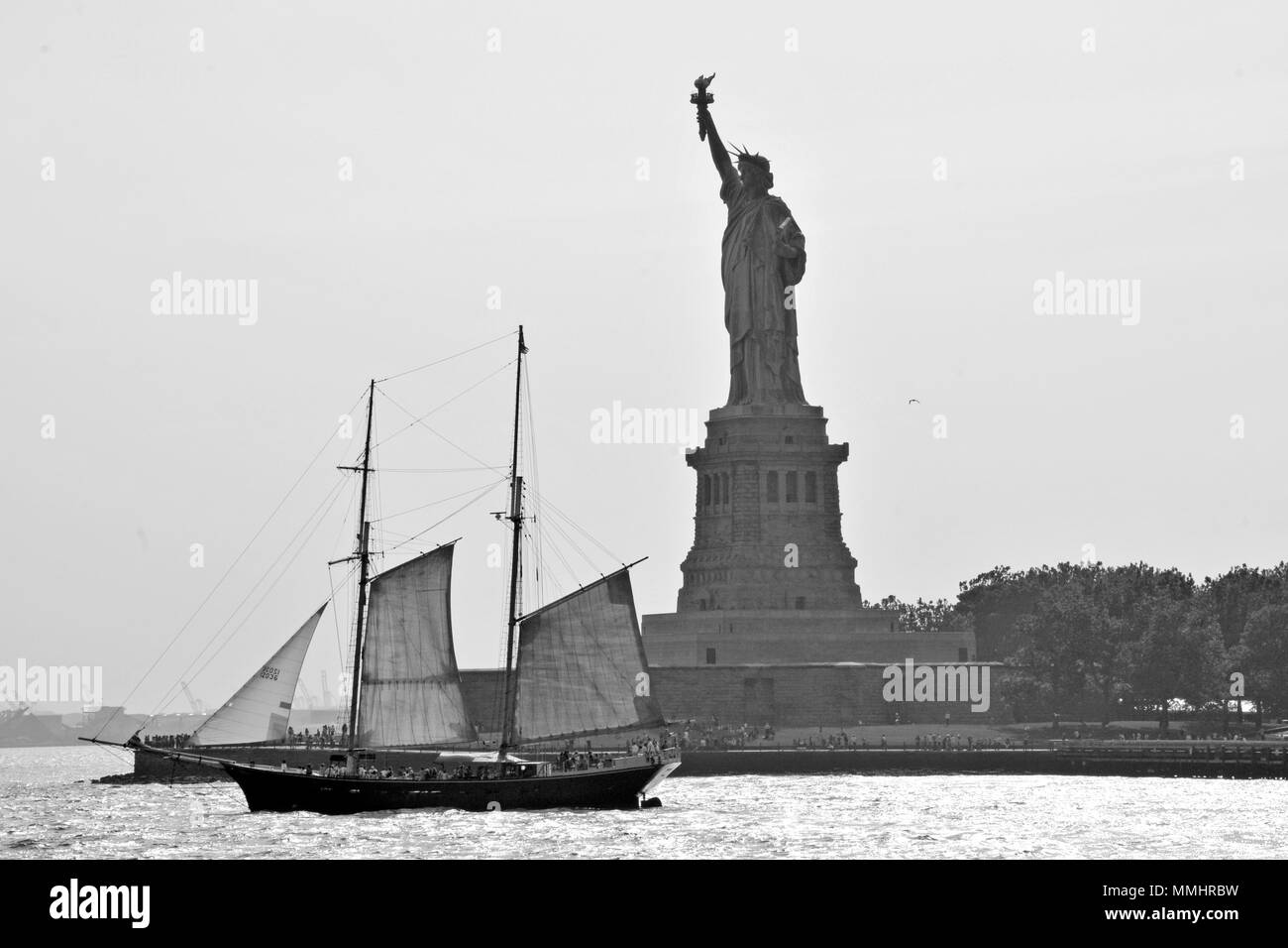 Un vieux voilier navigue en face de la Statue de la liberté à l'entrée du port de New York, New York, USA Banque D'Images