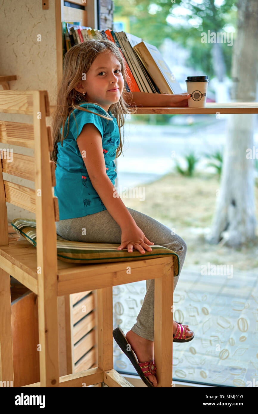 Petite fille de boire du café à la table Banque D'Images