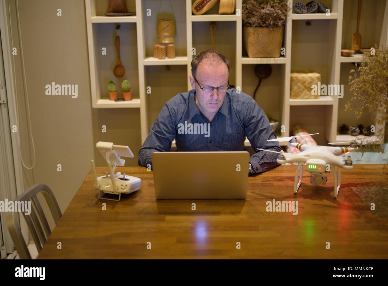 Homme mature avec bourdon et ordinateur portable dans la salle à manger à la maison Banque D'Images