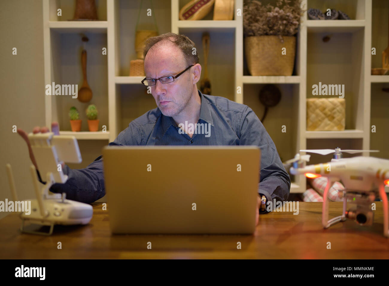Homme mature avec bourdon et ordinateur portable dans la salle à manger à la maison Banque D'Images