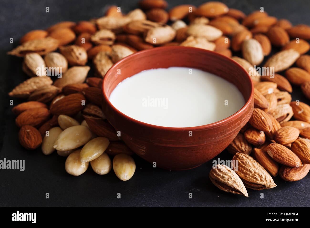 Le lait d'amande dans un pot en argile et des écrous sur ardoise foncé background, selective focus. Végétalien, sans produits laitiers alimentation saine notion Banque D'Images