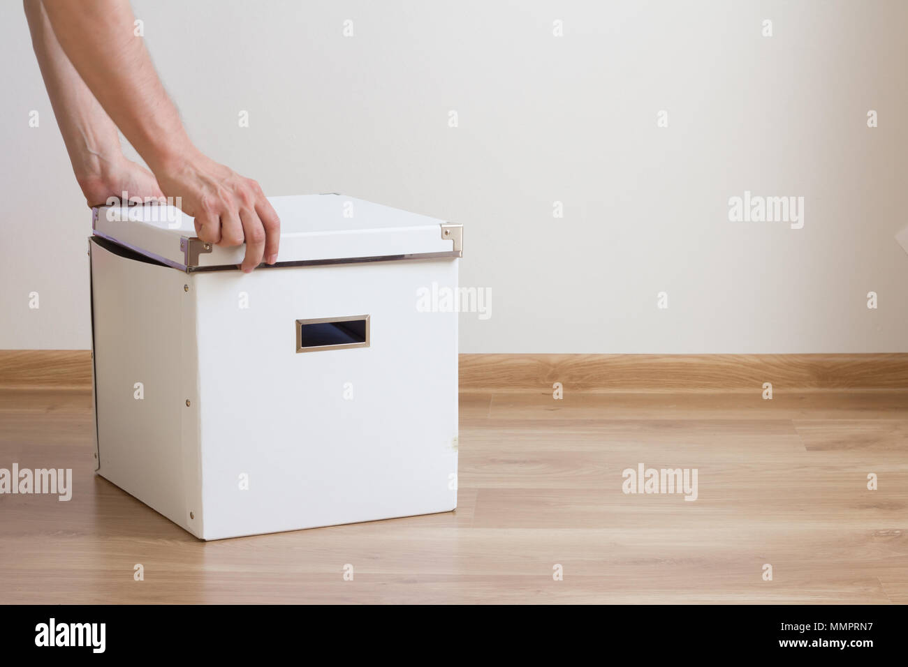 Ouverture mains boîte blanche sur le plancher dans salle vide Banque D'Images