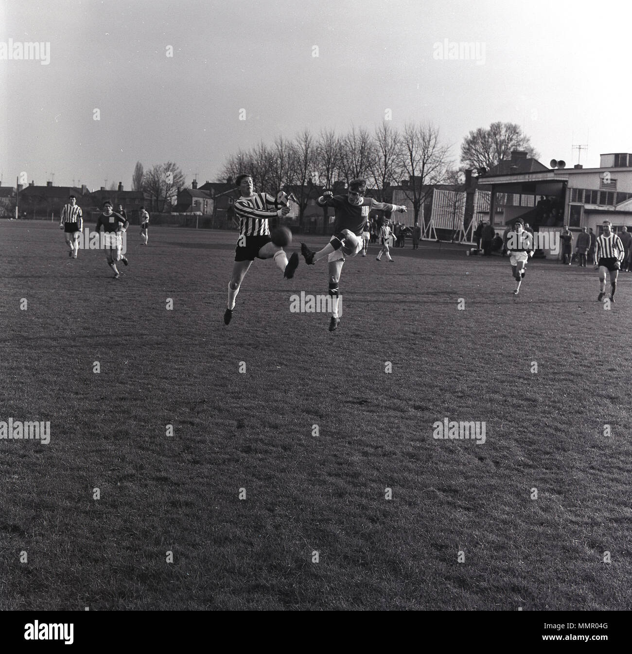 Années 1950, photo historique montrant les joueurs adultes de sexe masculin  à l'extérieur sur un terrain en herbe de jouer un match de football amateur  de la ville locale, England, UK. Il