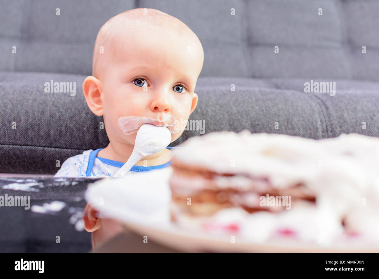 Premier anniversaire d'un petit garçon. Petit garçon de manger le gâteau d'anniversaire avec une cuillère, joyeux anniversaire. Tout-petit à table avec un gâteau. Banque D'Images