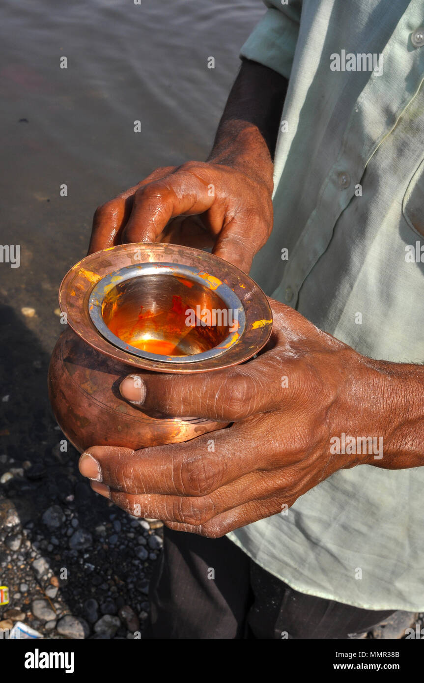 Baneshwar, Dungarpur, Rajasthan, Inde- 14 février 2011 : un dévot holding safran dans un pot en laiton pour le rituel traditionnel Baneshwar. Banque D'Images