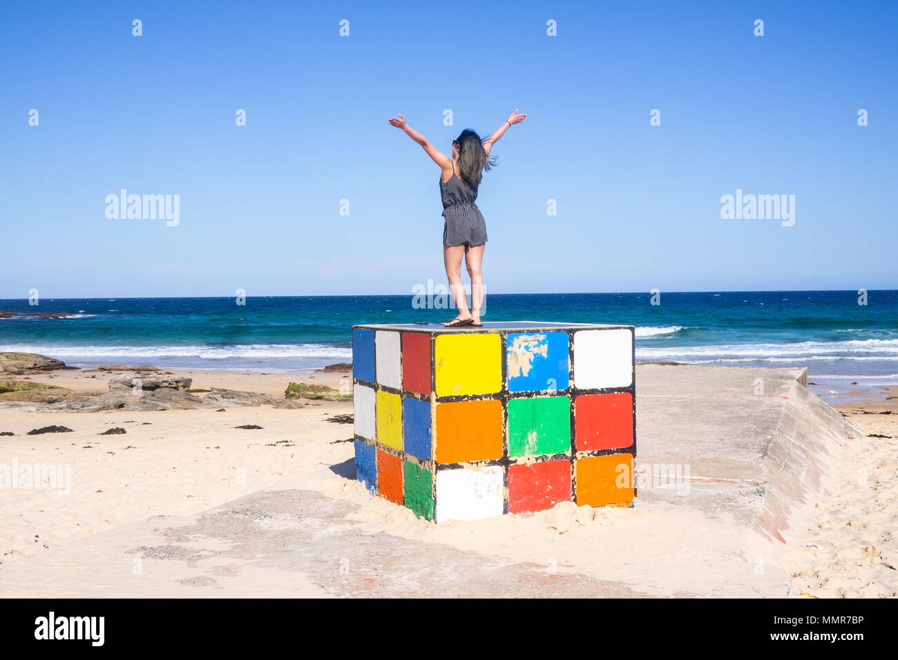 Jeune femme se dresse sur Rubik cube géant à Maroubra Beach, Sydney, Australie Banque D'Images